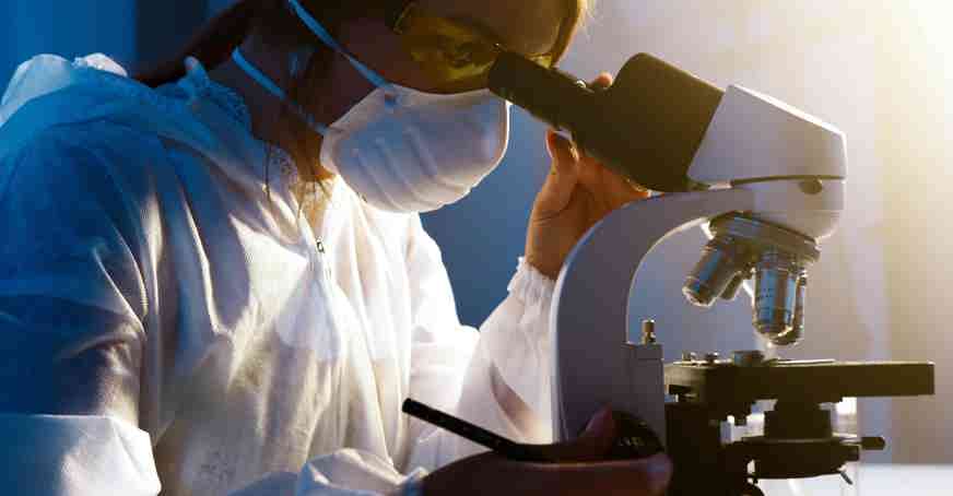 Scientist looking through a microscope in a lab