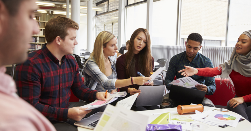 Students assembled around a table and engaged in a group study session.