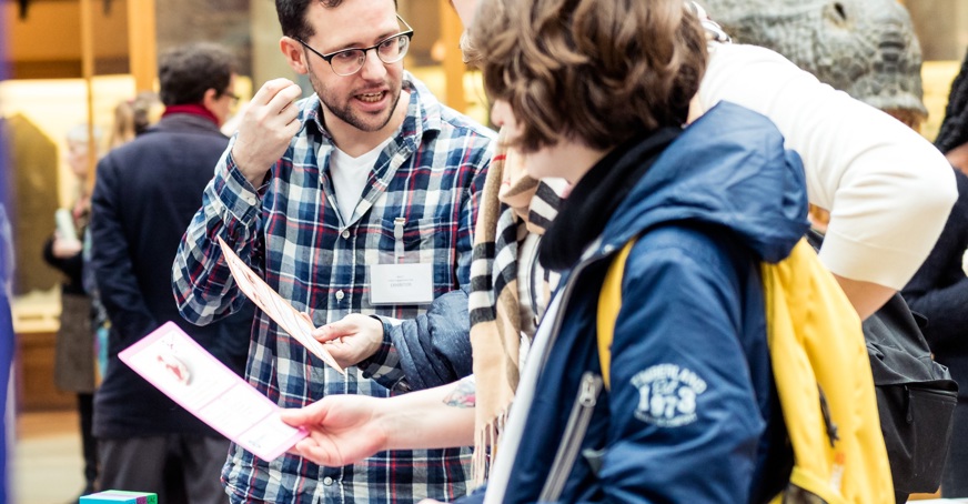 Science communicator talking to school children about genetics at a science fair