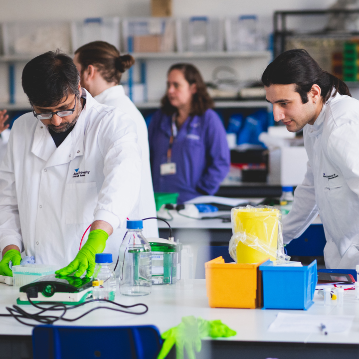 A group of individuals in laboratory coats collaborating on a scientific project in a laboratory setting