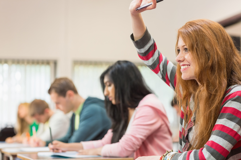 Image of a girl putting her hand up in a classroom