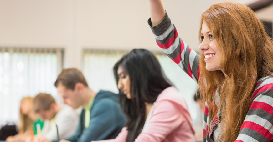 Undergraduate student with their hand up in a lecture