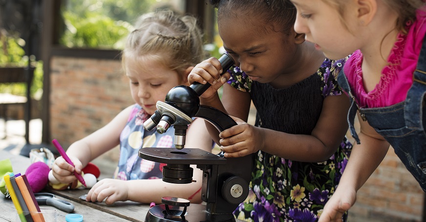 Three children using a microscope